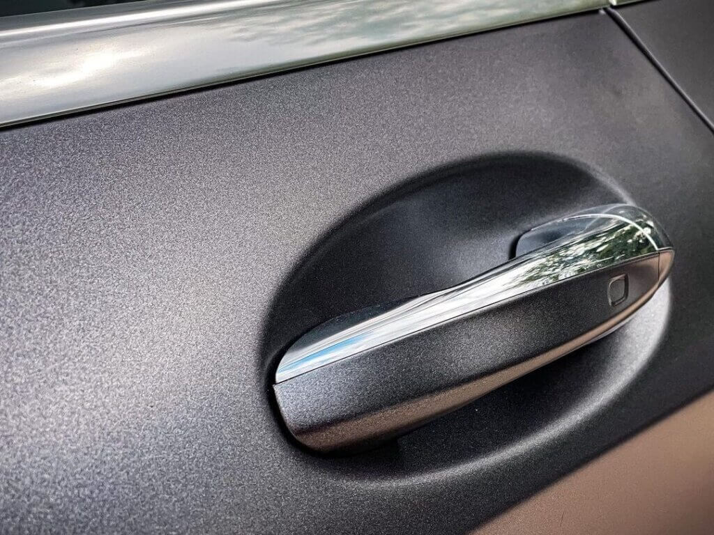 Poign&eacute;e de porte de voiture argent&eacute;e sur fond noir.