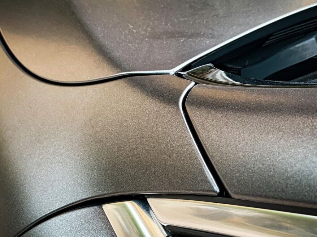 D&eacute;tail lumineux d'une carrosserie de voiture grise.